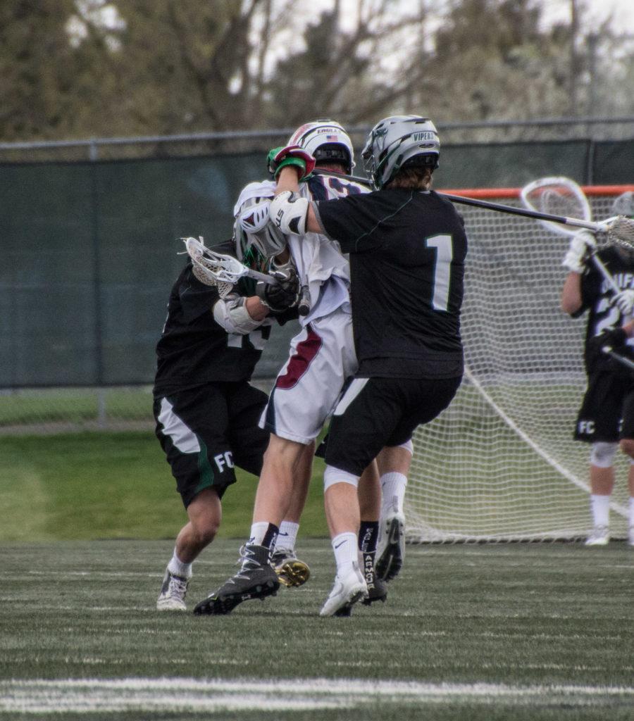 #1 Evan Bostrom and #15 Angelo Vattano crushing an attackmen driving towards the goal.