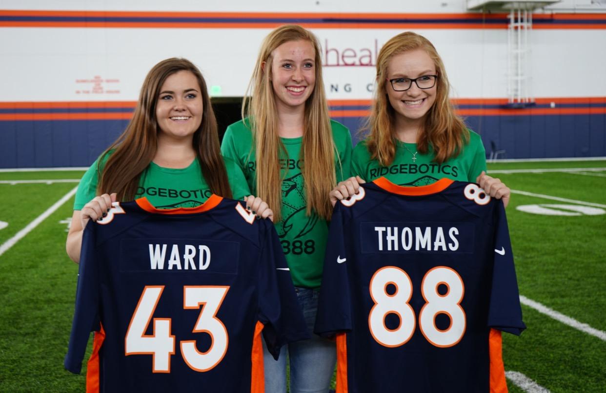 Bri, Kim, and Kennedy pose with Broncos jerseys.
