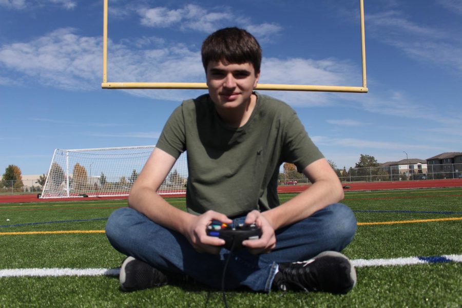 Brent Jones poses in front of the Fossil Ridge football fields goal post with a controller