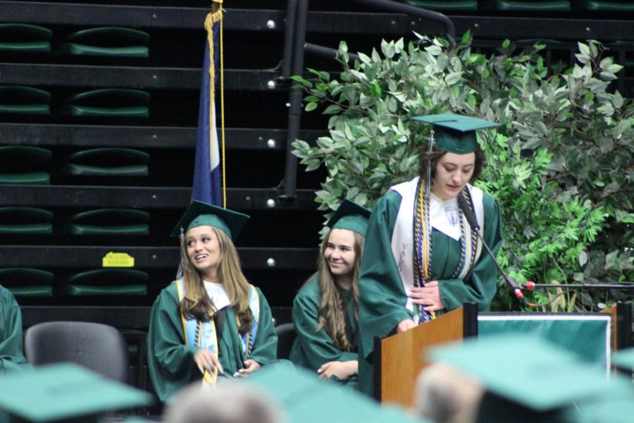 Class officers, Kyra Rivera and Emma Van Thorre look on as class vice president Cami Lovelace instructs grads to transfer their tassels