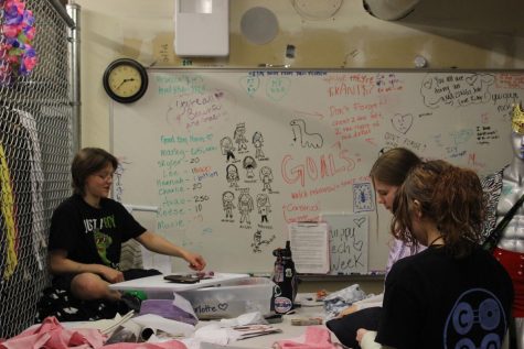 Costume crew organizes costumes in front of their planning whiteboard. 