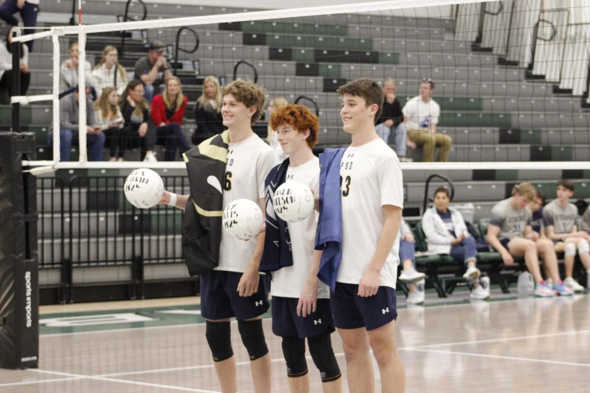 Seniors Alex Van Thuyne, Ty Morris, Owen Jacobson stand together on Senior Night with their flags over their shoulder of the colleges they will be attending in fall 2024, April 23. 
