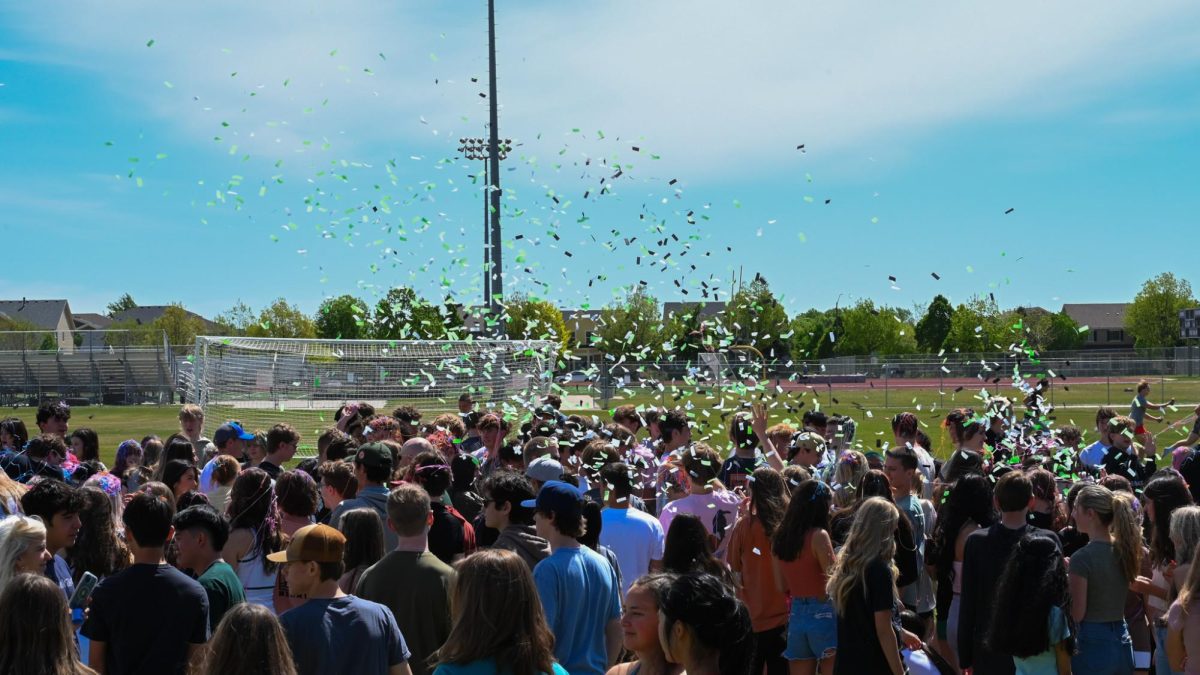 School provided confetti in Fossils green, black, and white is thrown  by seniors as they go through the student tunnel.
