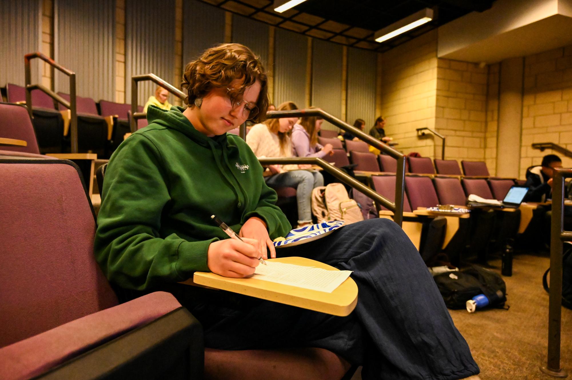 Senior Lily Siple works on blackout poetry during Poetry and Pastry Night. The words “victory” and “was not meant for you” stood out to her for the poem’s start.