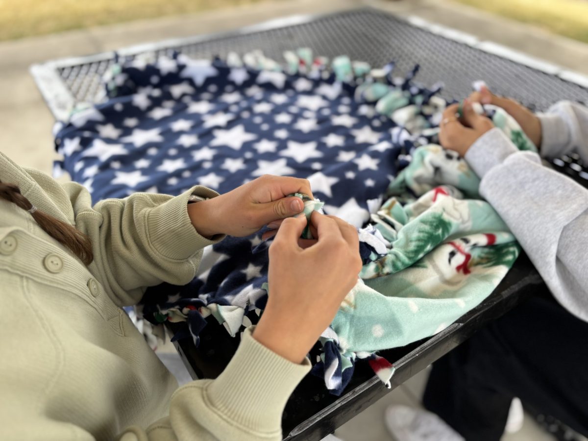 Tying the fleece blankets, Reese Morgan and Makena Phillips work together to donate blankets to the Children's Hospital Colorado.