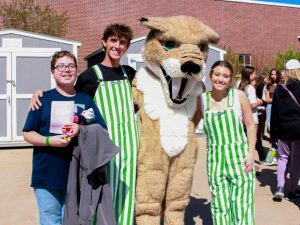Leadership, in their stripped green overalls, and Fang pose with an eighth grader.