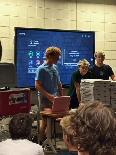 Three club presidents stand by stacks of pizza for students who attend Game Time Club every Friday lunch. 
