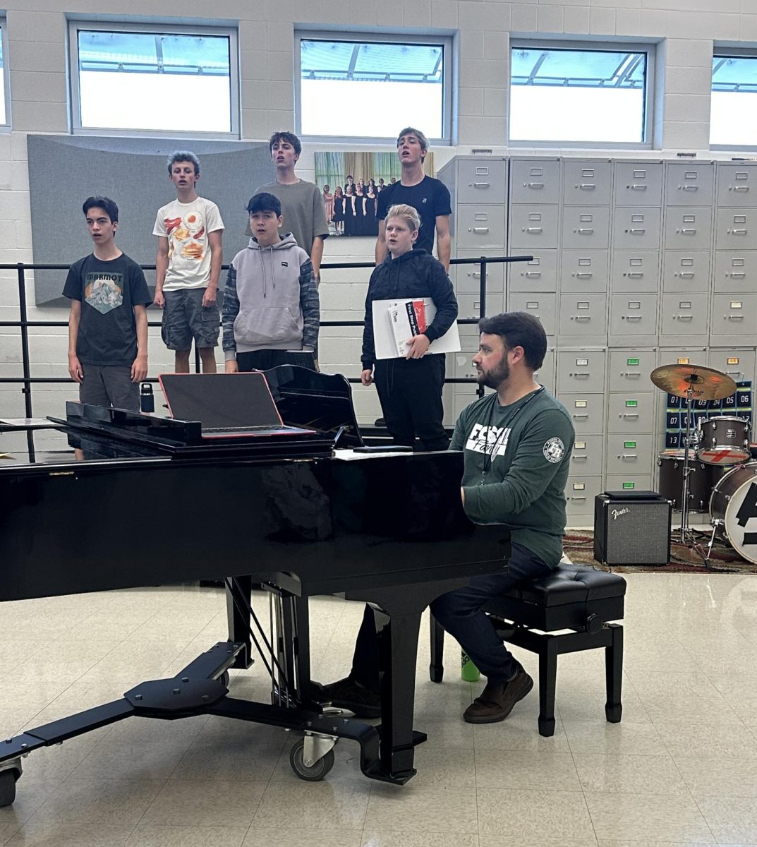  Joel Atella plays piano to help choir students warm up their voices before singing.

