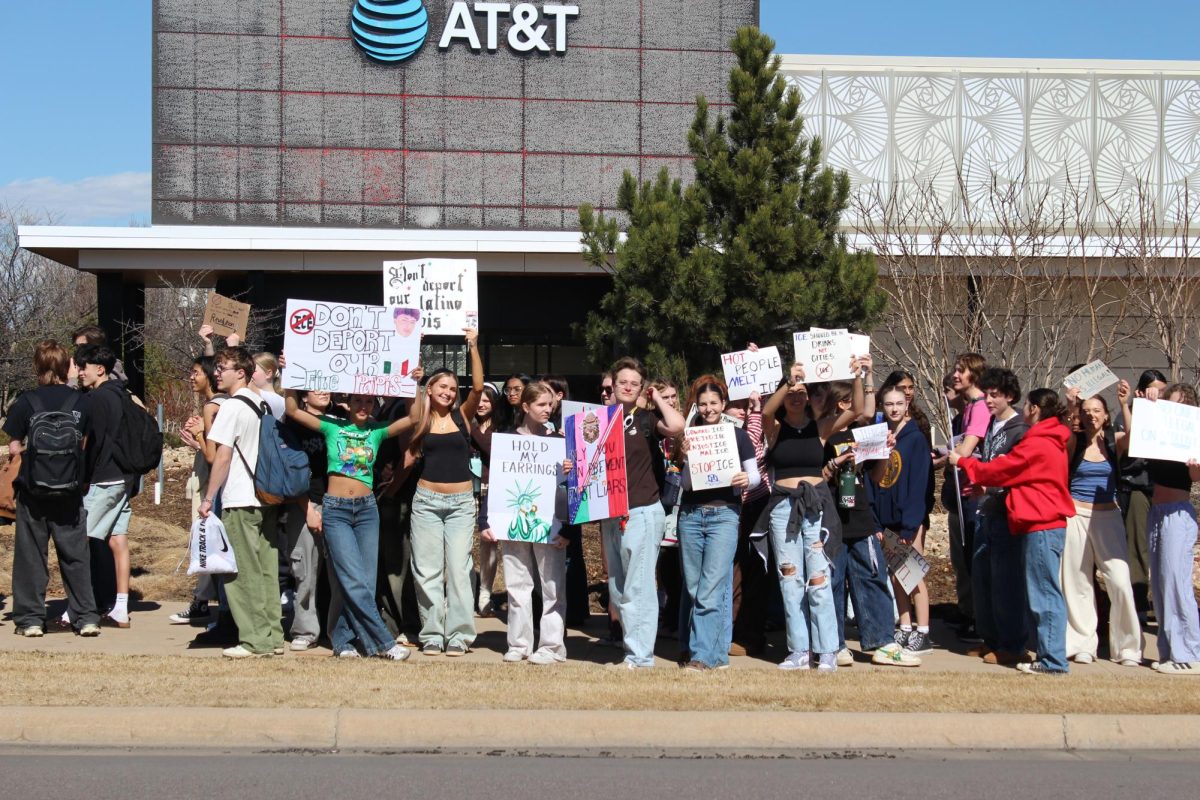 A group of protesters gather near an intersection, waving their signs as cars honk their horns in support. 